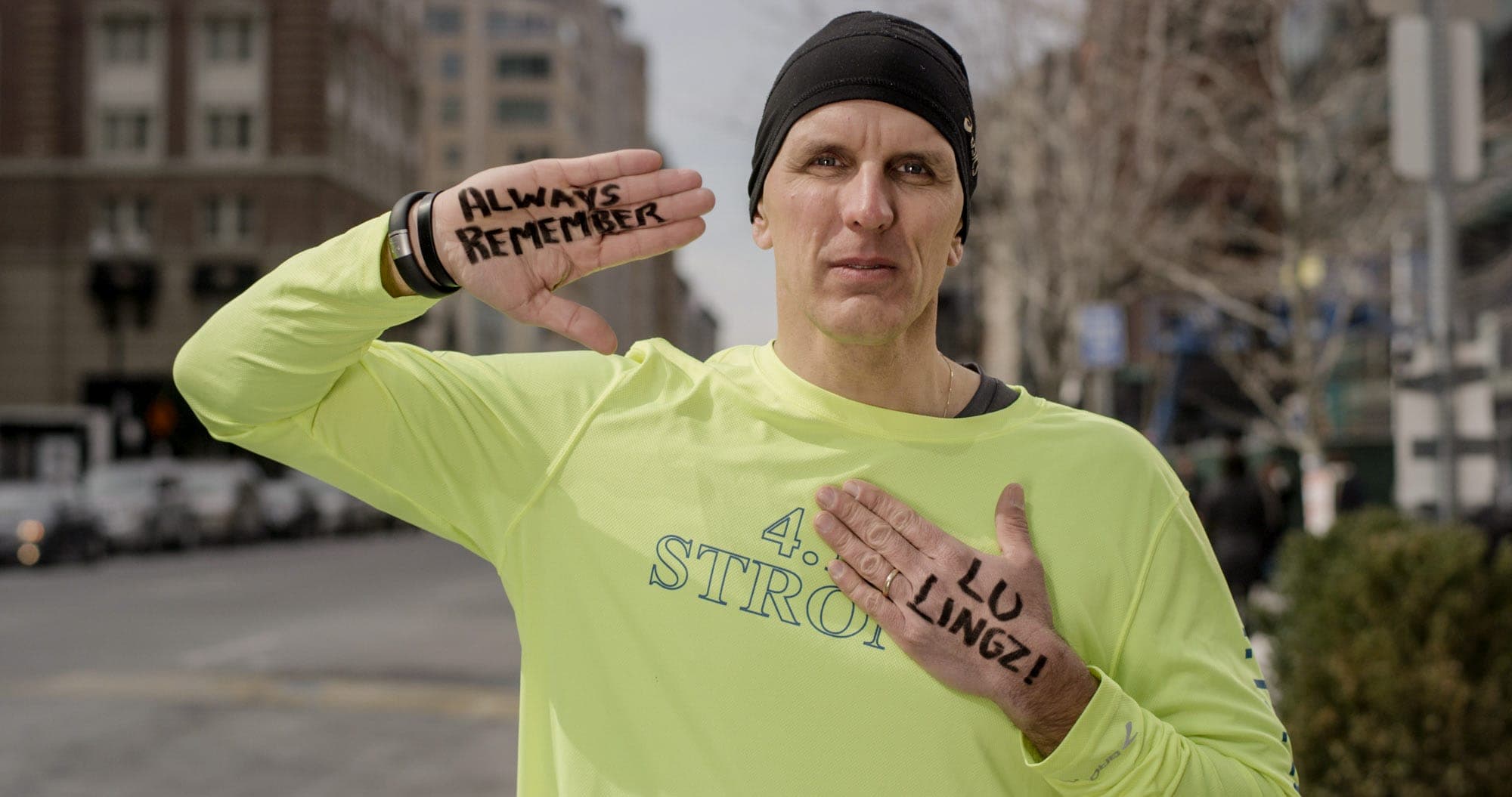 Dave Fortier, Marathon Survivor holding the message "Always remember Lu Lingzi" at the Boston Marathon finish line