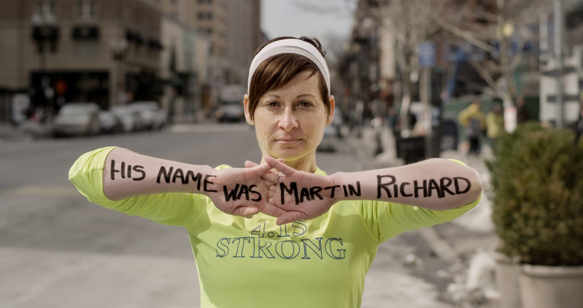 Lee Ann Yanni, Marathon Survivor holding the message "His name was Martin Richard" at the Boston Marathon finish line