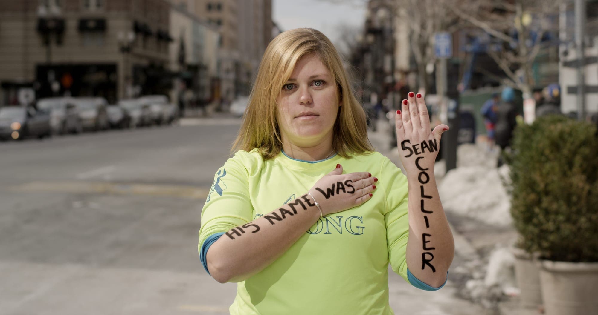 Elizabeth Bermingham, Marathon Survivor holding the message "His name was Sean Collier" at the Boston Marathon finish line