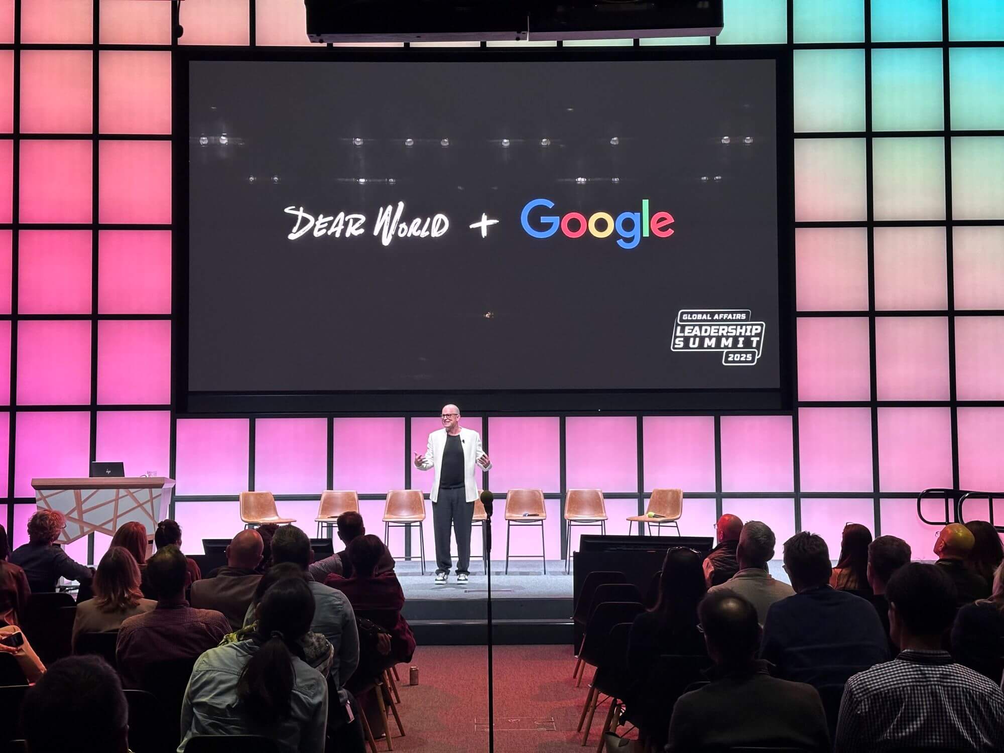 Robert Xavier Fogarty delivering an interactive keynote at a corporate conference with Dear World portraits displayed on screen