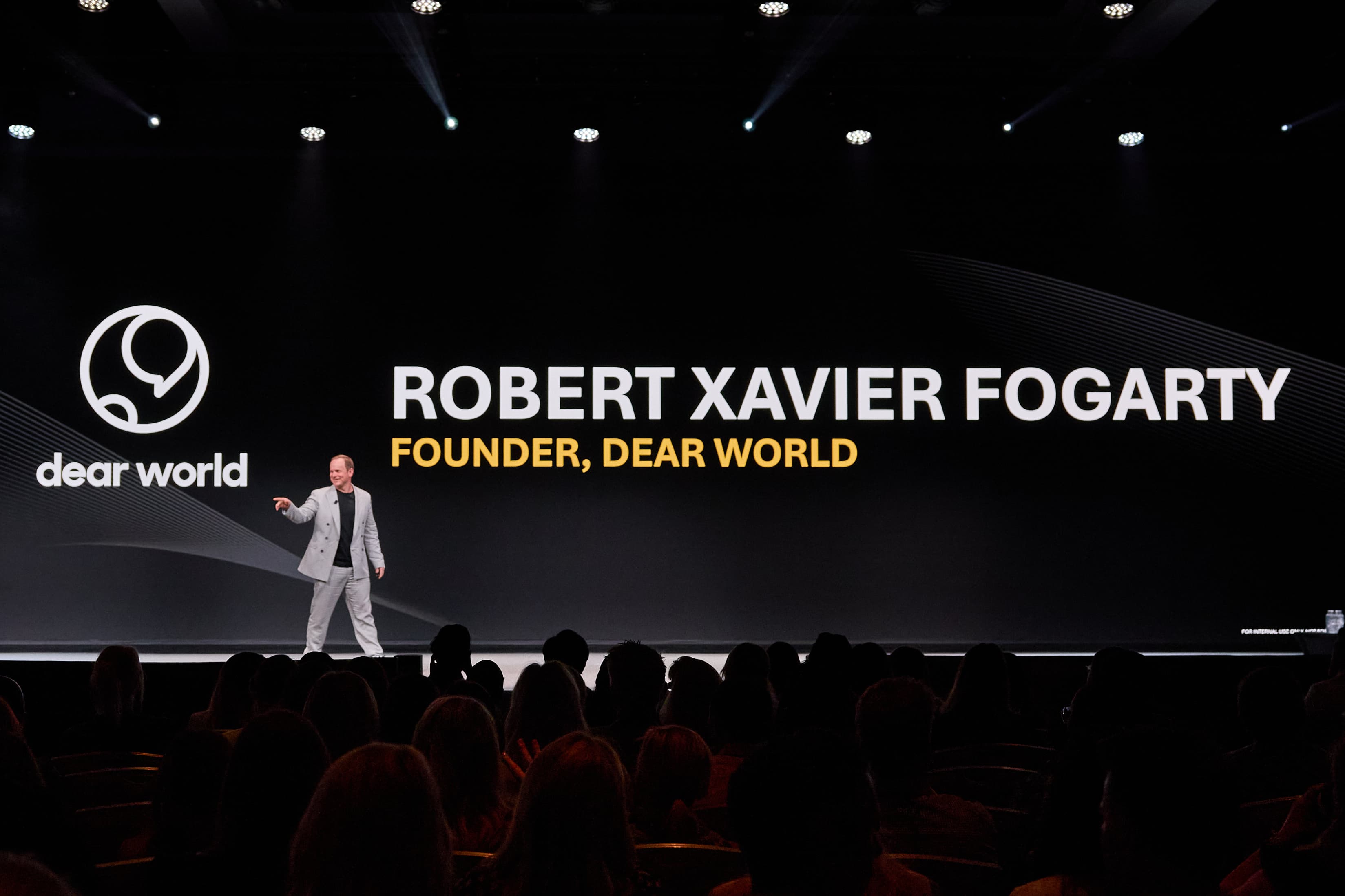 Robert Xavier Fogarty on a conference main stage with his name on the screen behind him